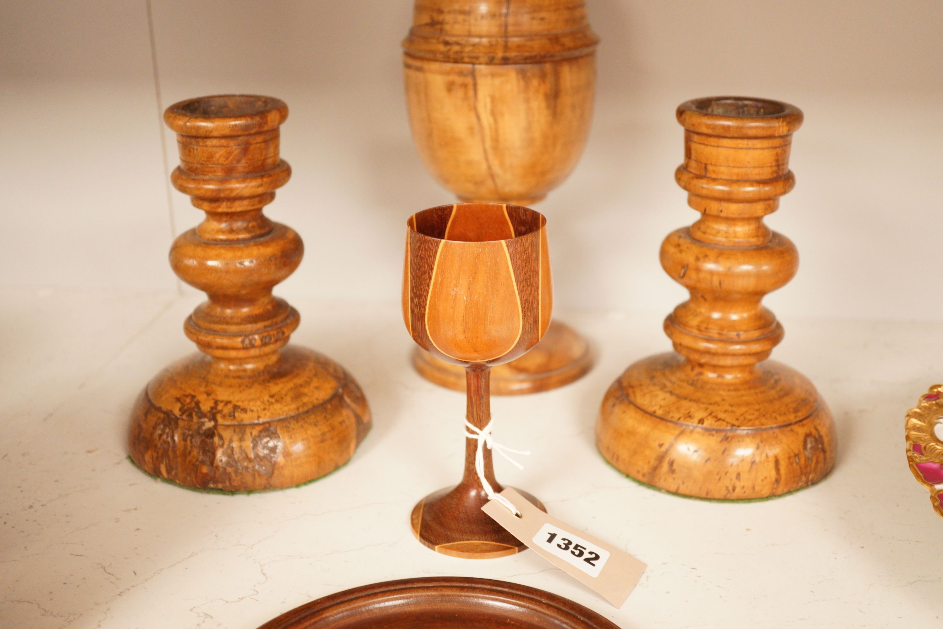 A treen goblet and cover, two candlesticks, a cup and a coaster